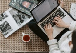 crop young businesswoman using laptop while drinking tea at home